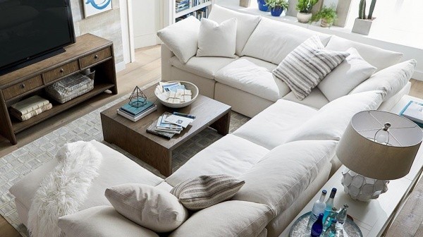 luxury living room featuring a white and wood color scheme with white sofa, white pillows, white counters, with brown wooden tv stand and coffee table