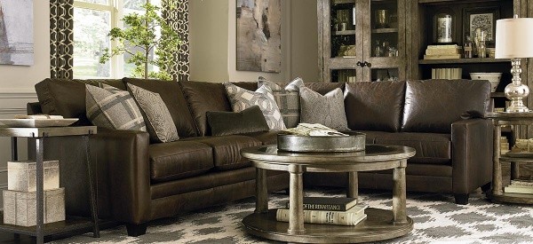 luxury living room featuring wraparound brown leather sofa with round wooden table with diamond patterned area rug