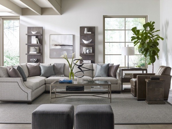 luxury living room featuring grey color scheme with grey sofa, grey ottomans, brown leather chair and grey rug