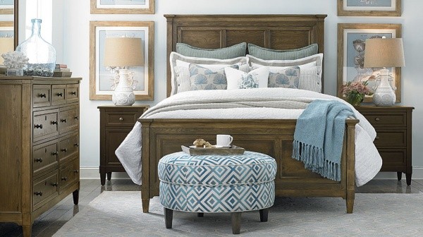 luxury finished interior bedroom with light brown wooden bed frame, armoire and nightstands with cyan and white colored ottoman