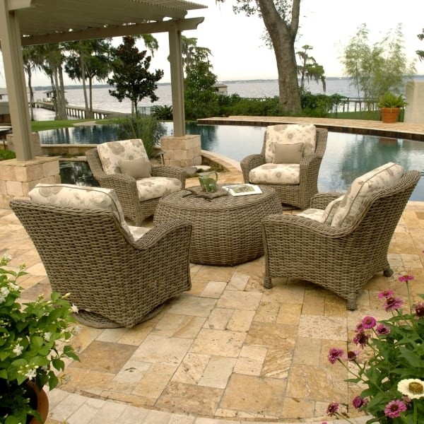 luxury patio including brown and tan wicker chairs with rounded wicker center table overlooking swimming pool