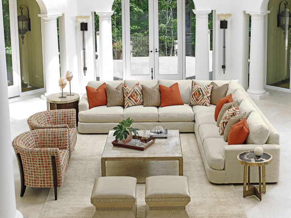 luxury living room featuring off white color scheme with cream wraparound sofa, cream ottomans, cream tables and orange and cream chairs