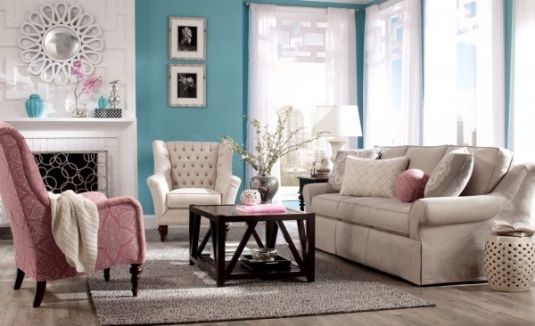 luxury living room featuring with off white sofa, pink chair, and off white chair with wooden table and teal walls