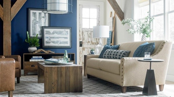 luxury living room featuring blue and white color scheme with cream colored sofa with blue pillows, brown leather chairs, and wooden luxury furniture