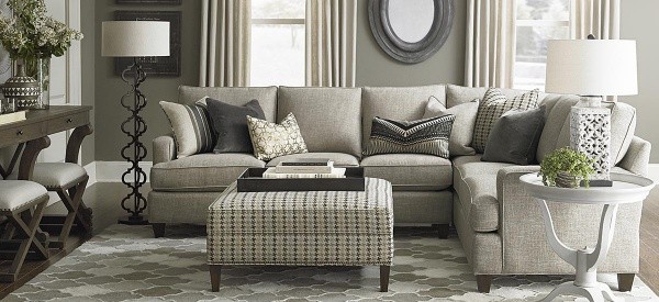 luxury living room featuring light brown color scheme with wraparound sofa with pillows, material table, and multicolored honeycomb pattern area rug