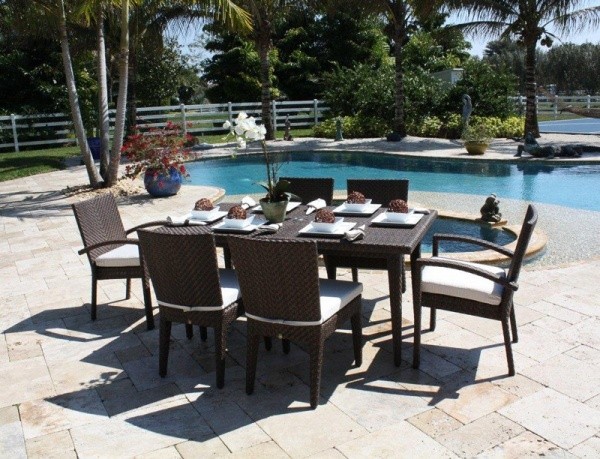 luxury patio including dark brown wicker outdoor dining table with six chairs next to the swimming pool