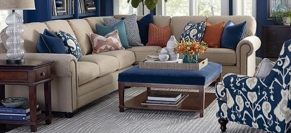 luxury living room featuring featuring tan wraparound sofa with blue table and blue patterned chair with woodgrain pattern grey rug