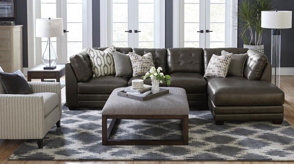 luxury living room featuring luxury leather sofa, diamond pattern area rug, and white striped chair