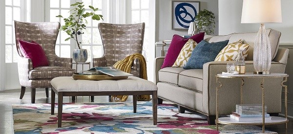 luxury living room featuring off white couch and table, with vibrantly colored rug and two brown patterned chairs