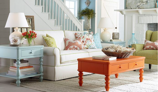 luxury living room featuring a white sofa with multi colored pillows and orange wooden table, light blue end table and olive green chair