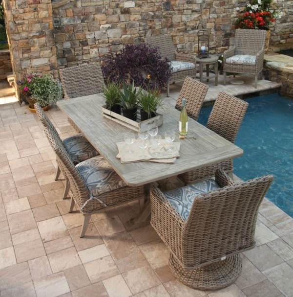 luxury patio including wood and wicker outdoor dining set, with a bottle of wine ready to be poured